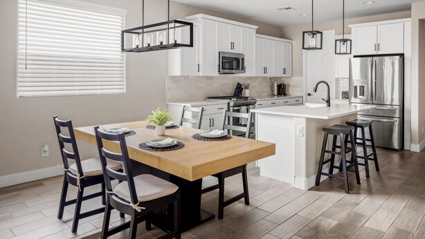 A modern kitchen with white cabinets, stainless steel appliances, and a wooden dining table. - 3 BR home w/Pool & Game room (Phoenix)