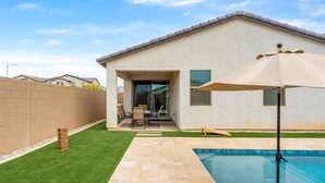 A backyard with a swimming pool, a patio with a table and chairs, and a brick wall. - 3 BR home w/Pool & Game room (Phoenix)