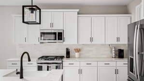 A modern kitchen with white cabinets, a stainless steel refrigerator, a microwave, and a gas stove. - 3 BR home w/Pool & Game room (Phoenix)