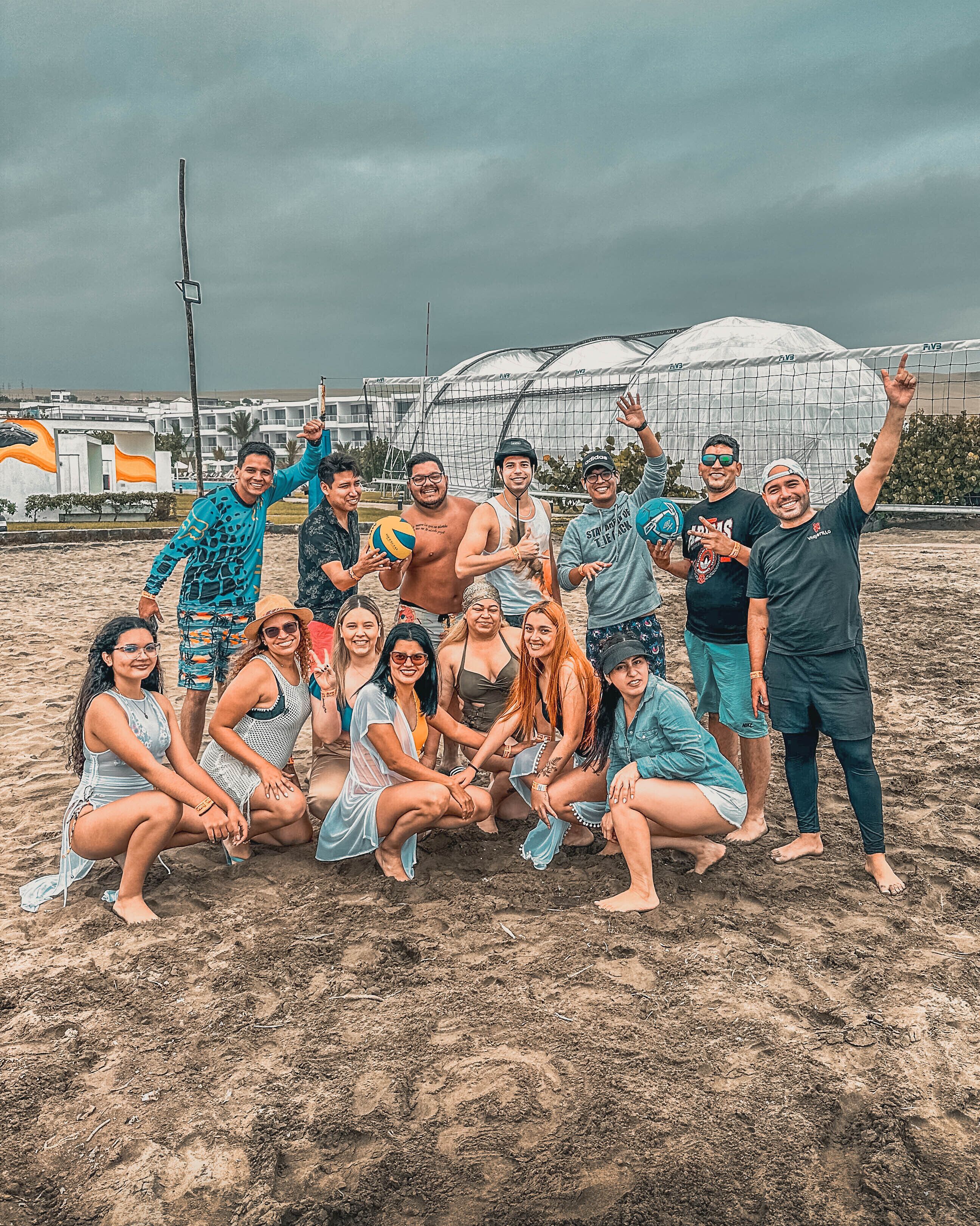 Un grupo de personas en una playa arenosa con una carpa grande al fondo.