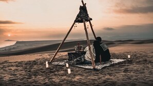 A tent set up on a sandy beach with a view of the ocean and distant mountains.