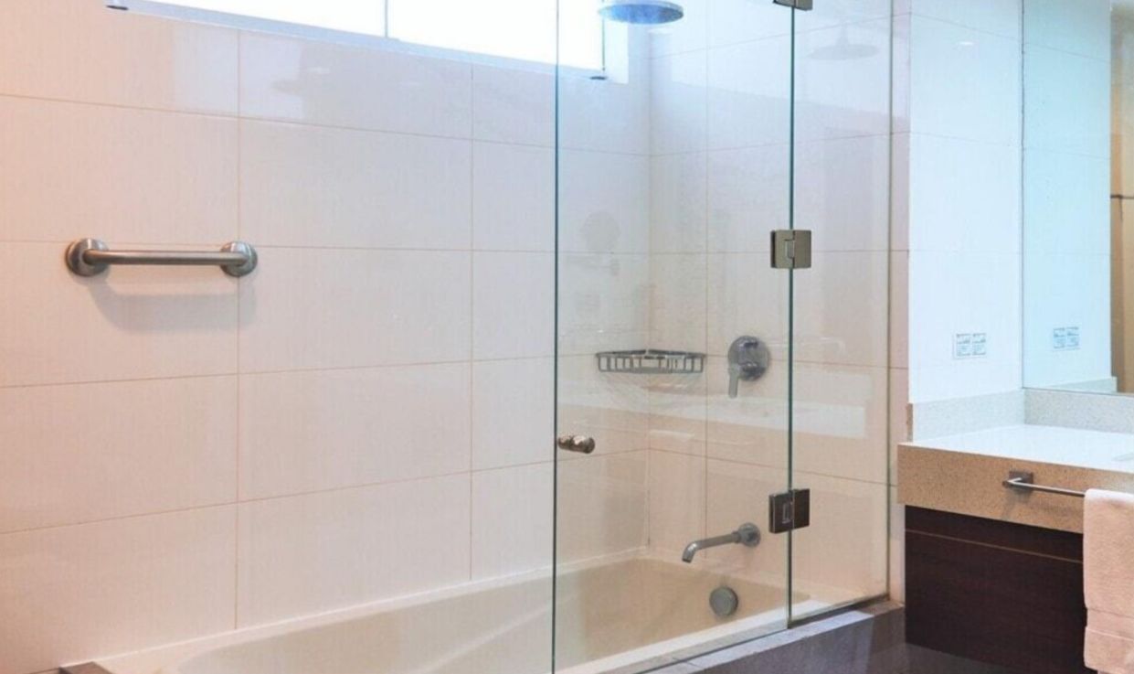 A modern bathroom with a glass-enclosed shower, a towel rack, and a visible toilet paper holder.