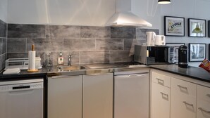 A modern kitchen with grey tiles, stainless steel appliances, and white cabinetry.