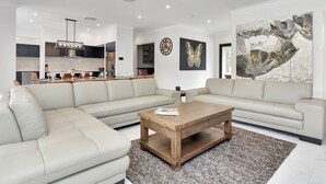 A modern living room with a sectional sofa, a wooden coffee table, and a large abstract painting.