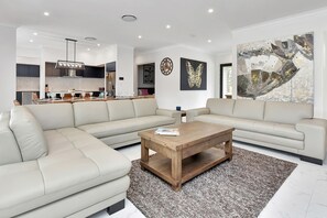 Een moderne woonkamer met een hoekbank, een houten salontafel en een groot abstract schilderij.