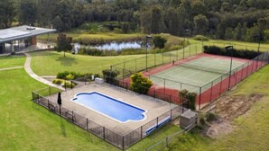 A tennis court, a swimming pool, and a building with a covered walkway.
