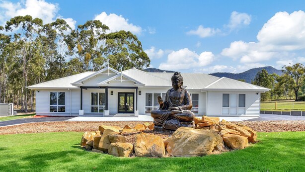 A modern house with a large Buddha statue in front.