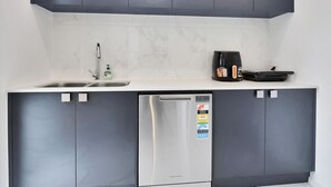 A compact kitchen with a dishwasher, a coffee maker, and a sink.