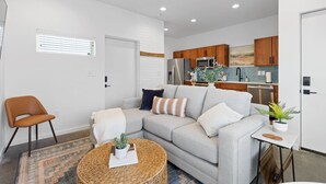 A modern living room with a grey sofa, a brown chair, a woven coffee table, and a small side table with a plant. - Golden Hour - A Southside Home (Chattanooga)
