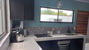 Cozinha moderna com armários escuros, uma pia dupla, forno embutido e janela com vista para o exterior.