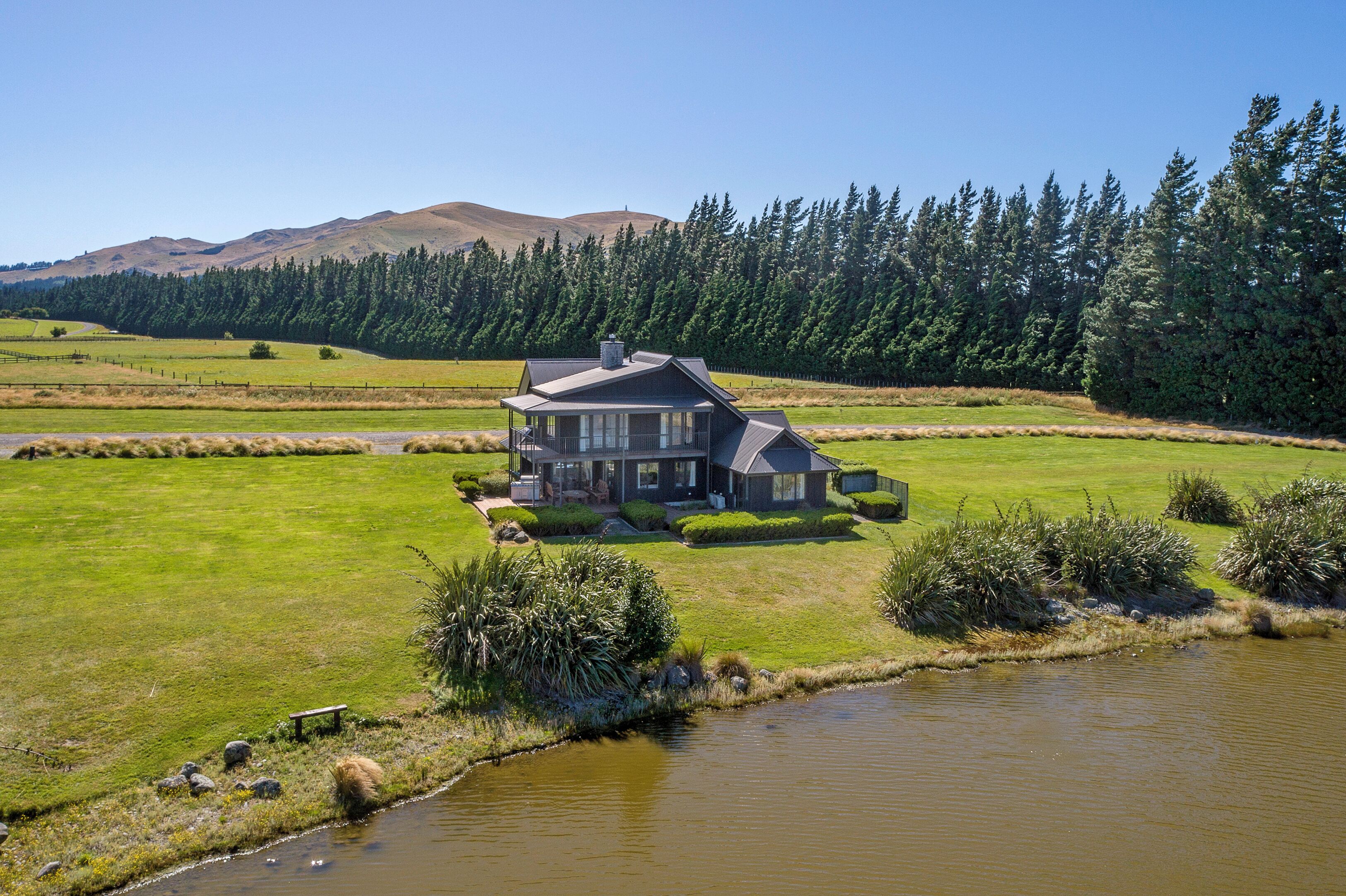 Uma casa grande com um amplo jardim e um lago em primeiro plano.