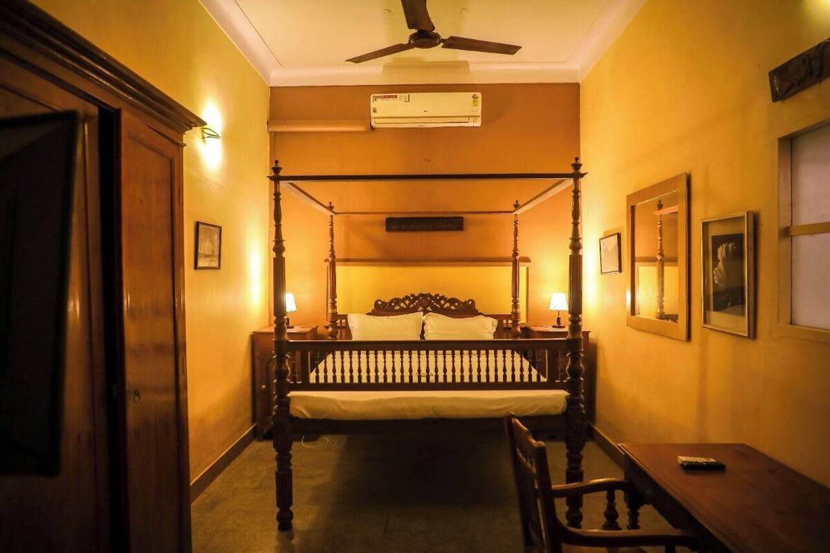 A four-poster bed with a wooden headboard, two bedside lamps, and a ceiling fan.