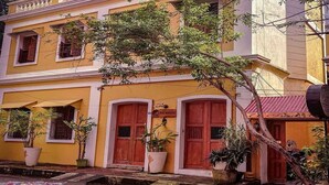 A yellow building with red doors and windows, potted plants, and a sign for 'French Club'. - The French Villa (Puducherry)