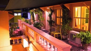 A balcony with potted plants, a chair, and a railing. - The French Villa (Puducherry)