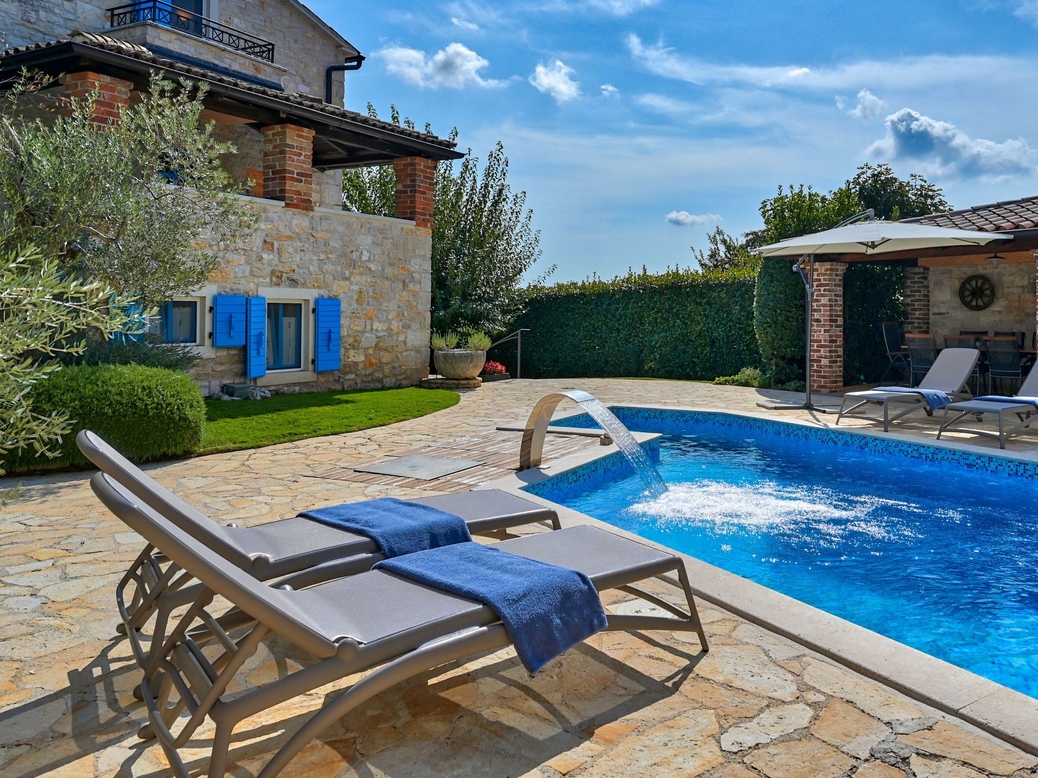 Une piscine avec des chaises longues et une terrasse en pierre.