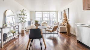 A modern living room with a dining table, chairs, a sofa, and a kitchen area. - Seattle`s modern and stylish Penthouse Apartment- Wifi, Pet Friendly, Rooftop (Seattle)