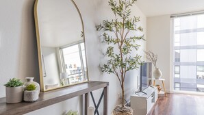 A modern living room with a large mirror, a potted tree, and a console table with decorative items. - Seattle`s modern and stylish Penthouse Apartment- Wifi, Pet Friendly, Rooftop (Seattle)