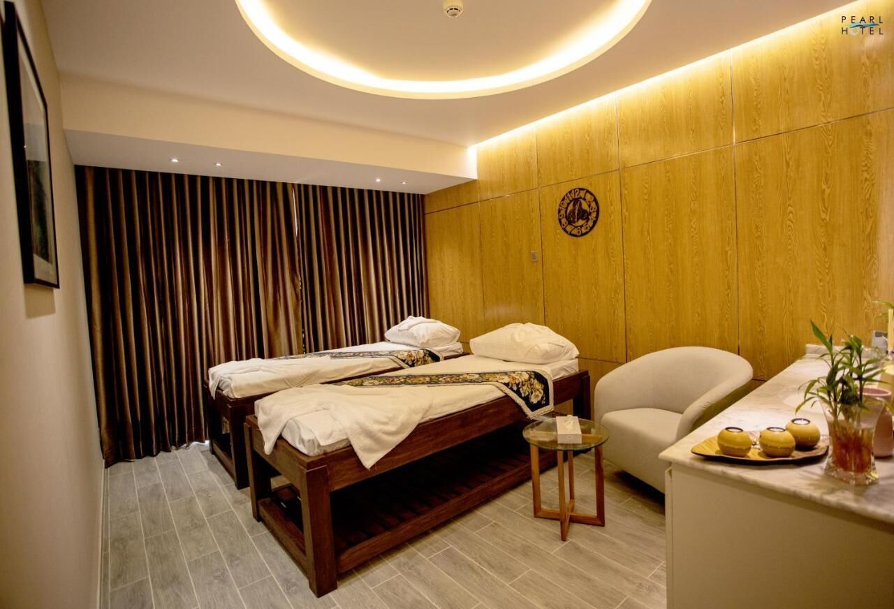 A hotel room with a bed, a small table, a chair, and a counter with a plant and a fruit display.