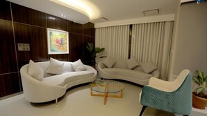 A modern living room with two white sofas, a glass coffee table, and a teal armchair. - Pearl Hotel Dhaka (Dhaka)