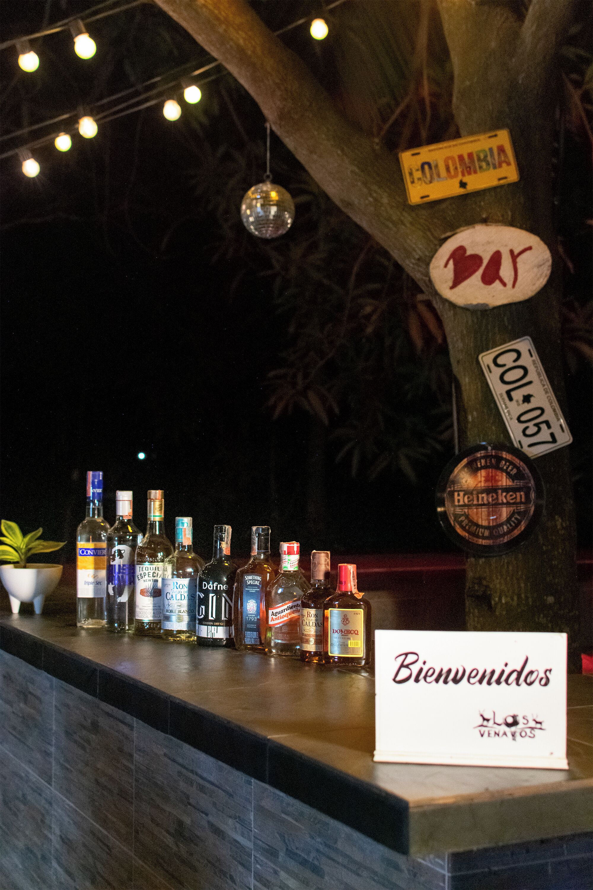 Una barra con diferentes botellas de licor y un letrero que dice 'Bienvenidos'.