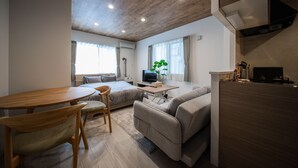 Ett modernt vardagsrum med ett träpanelat tak, en soffa, en tv och en matplats med ett bord och stolar.