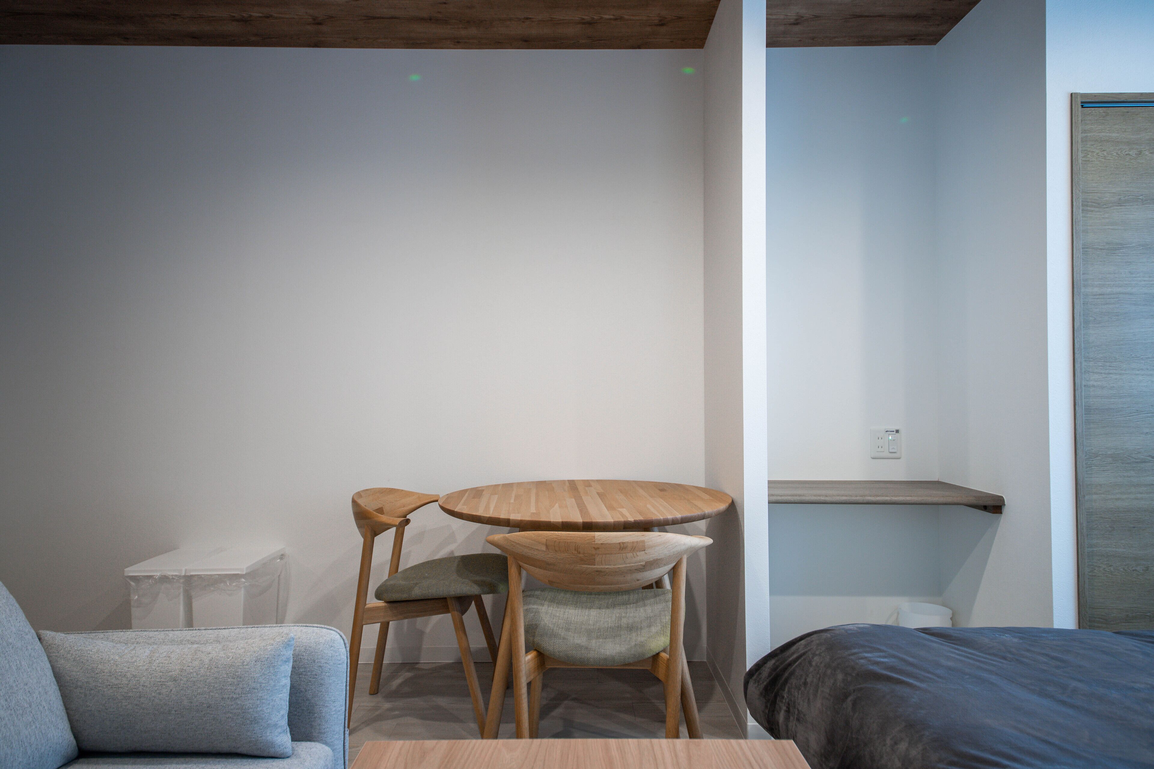 A modern room with a wooden table, two chairs, a sofa, and a bed.