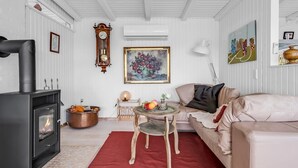 Una sala de estar acogedora con una chimenea moderna, un sofá cómodo, una mesita con un florero y un cuadro en la pared.