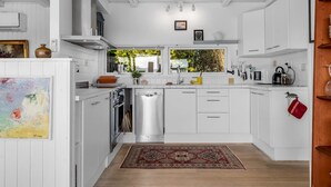 Una cocina moderna con armarios blancos, electrodomésticos de acero inoxidable y piso de madera.