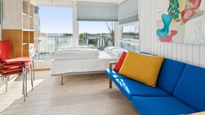 Un dormitorio moderno con una cama grande, un sofá azul y un balcón con vistas.