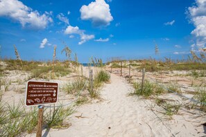 A sandy beach path with a sign advising to stay out of dunes and turn off lights. - Maritime Place (St. Augustine)