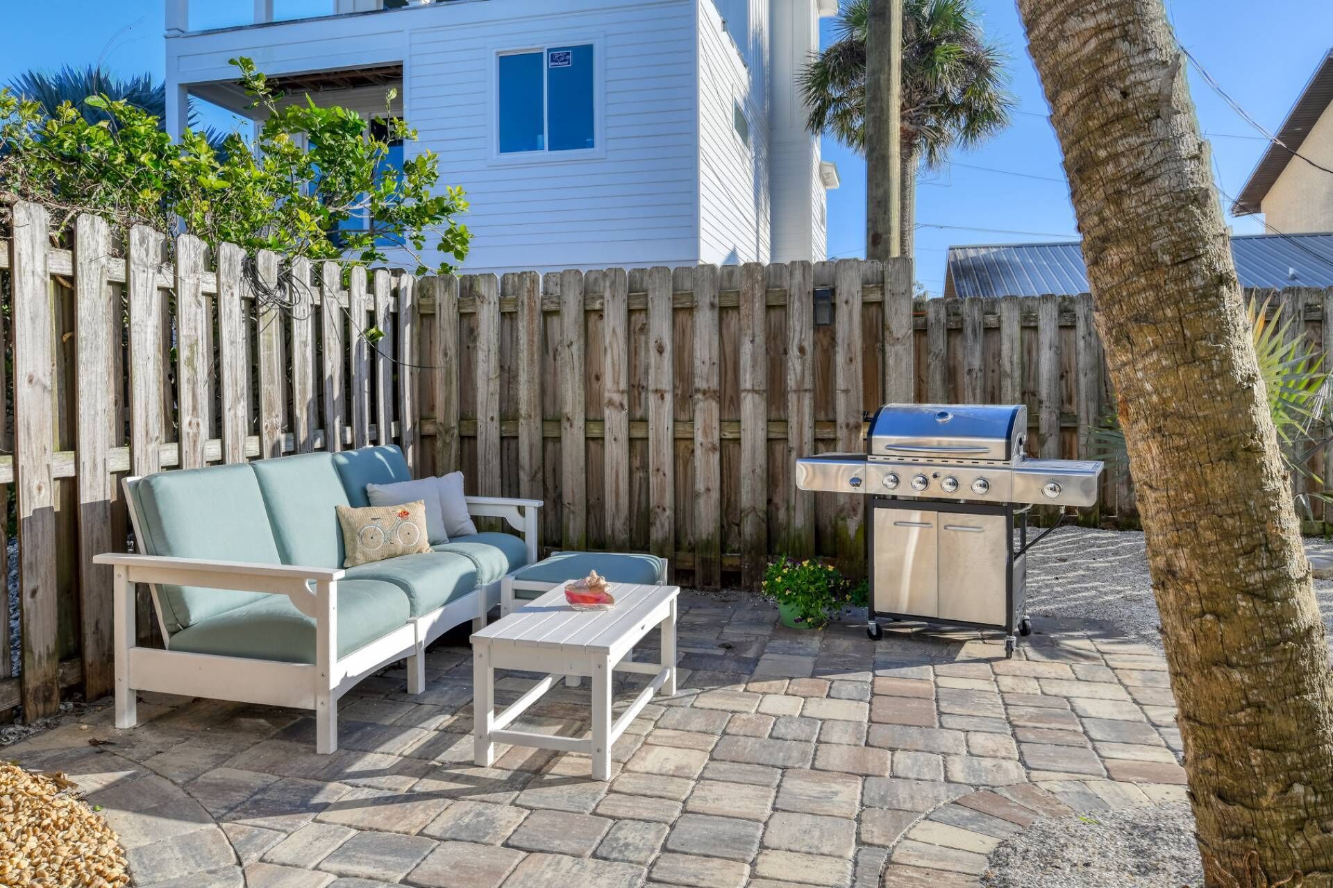 An outdoor patio with a white sofa, a small table, and a grill.