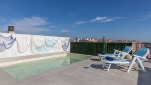 A rooftop pool area with a view of the city skyline, a decorative wall with net-like patterns, and lounge chairs. - Luxury Atic Cambrils by Interhome (Cambrils)