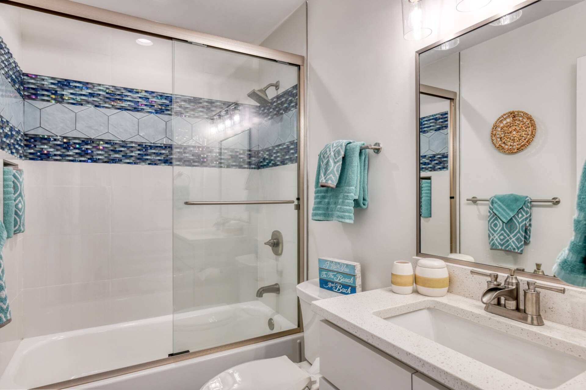 Ein modernes Badezimmer mit einer gläsernen Duschkabine, einer Badewanne und einem Waschtisch mit Waschbecken und Spiegel.