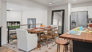 Eine moderne Küche mit Kochinsel, Edelstahlgeräten und einem Essbereich mit großem Tisch und Stühlen.