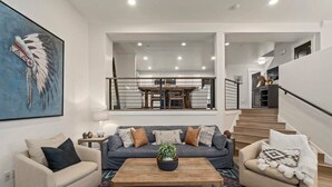 Ein modernes Wohnzimmer mit einer Couch, einem Couchtisch und einer Treppe, die in ein Obergeschoss führt.