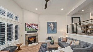 Ein modernes Wohnzimmer mit Kamin, großem Fernseher und gemütlicher Sitzecke.