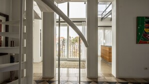 Ein geräumiger Innenraum mit einer Treppe zu einem Balkon, einer Küchenzeile und Blick ins Freie.