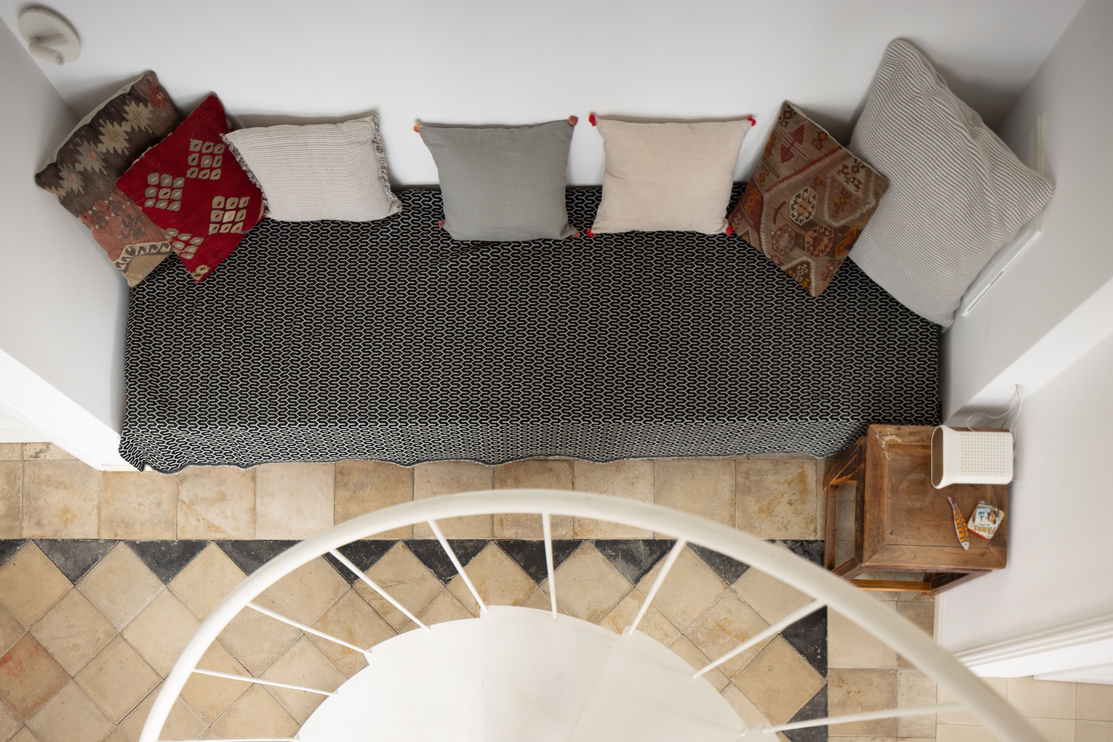 A modern living room with a sofa set, patterned cushions, and a staircase leading to an upper floor.