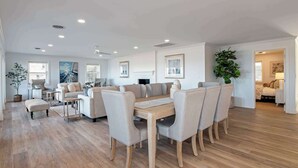 Un amplio salón con una gran mesa de comedor de madera rodeada por seis sillas, un conjunto de sofás y una chimenea.