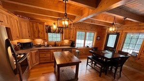 A wooden cabin interior with a kitchen, dining area, and large windows. - Prong Pond Cabin*Water Access*Pet Friendly*Snowmobile Access (Greenville)