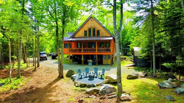 A cabin with a deck, surrounded by trees and a gravel path. - Prong Pond Cabin*Water Access*Pet Friendly*Snowmobile Access (Greenville)