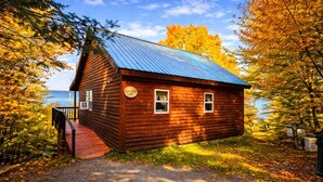 A wooden cabin with a metal roof, a porch, and a sign indicating it is a seasonal accommodation. - Seboomook-Lake/Mountain Views*Shared Dock*Kayaks*Hiking Trails*A/C (Greenville)