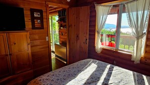 Ein Holzhüttenraum mit Bett, Fernseher und einem fenster mit Vorhängen.