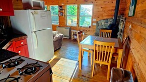 Un acogedor interior de cabaña con cocina, comedor y chimenea de piedra.