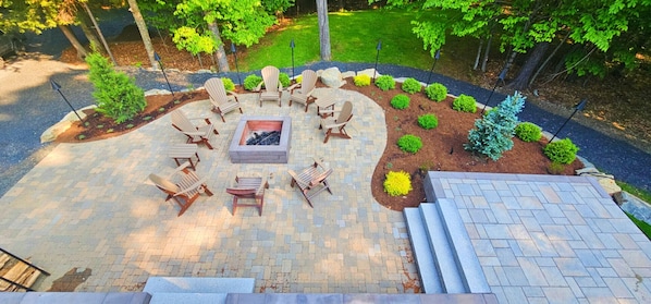 Un patio circular con sillas Adirondack, una fogata y una mesita.