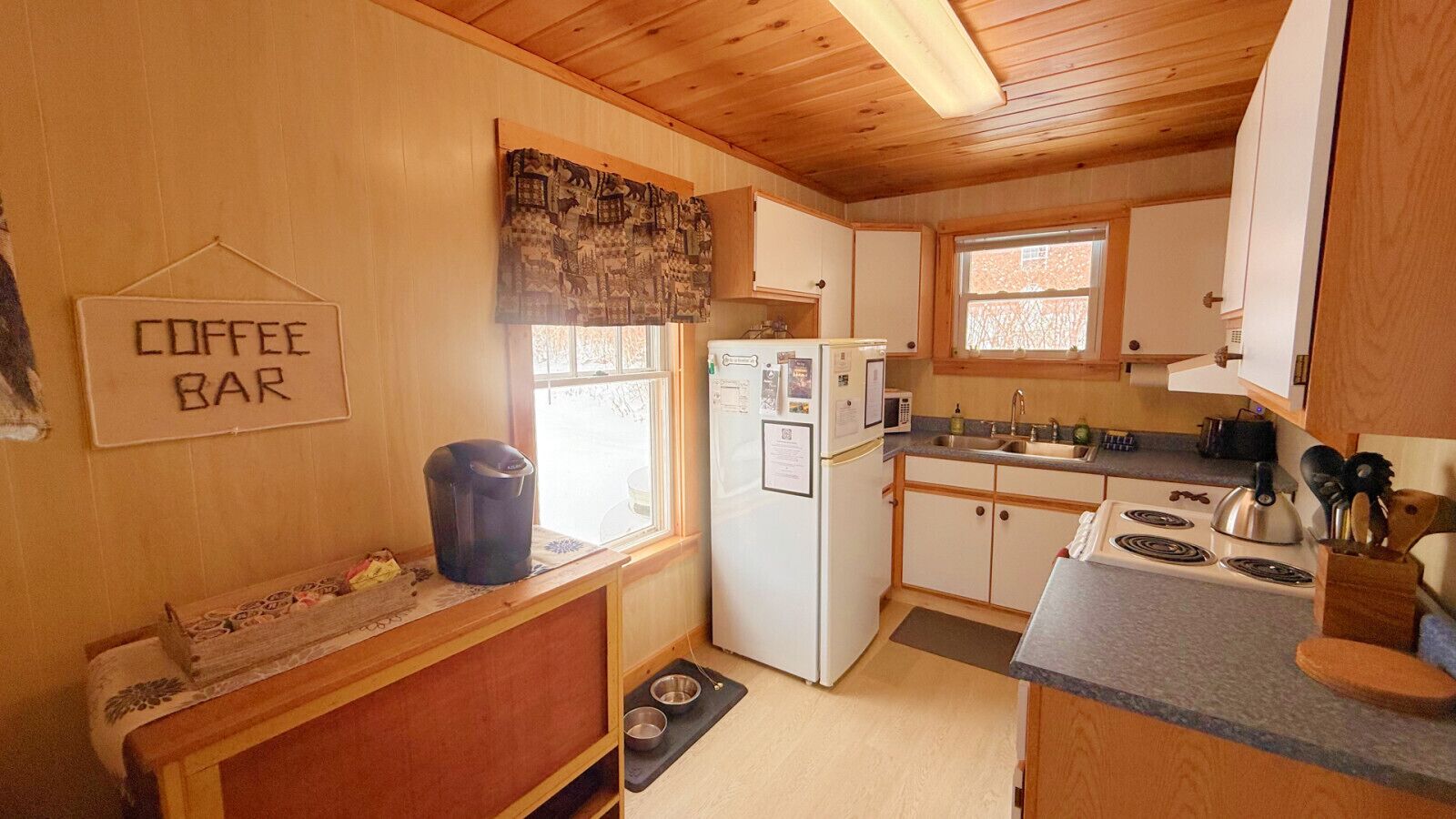 A compact kitchen with a coffee bar, a refrigerator, a stove, and a sink.