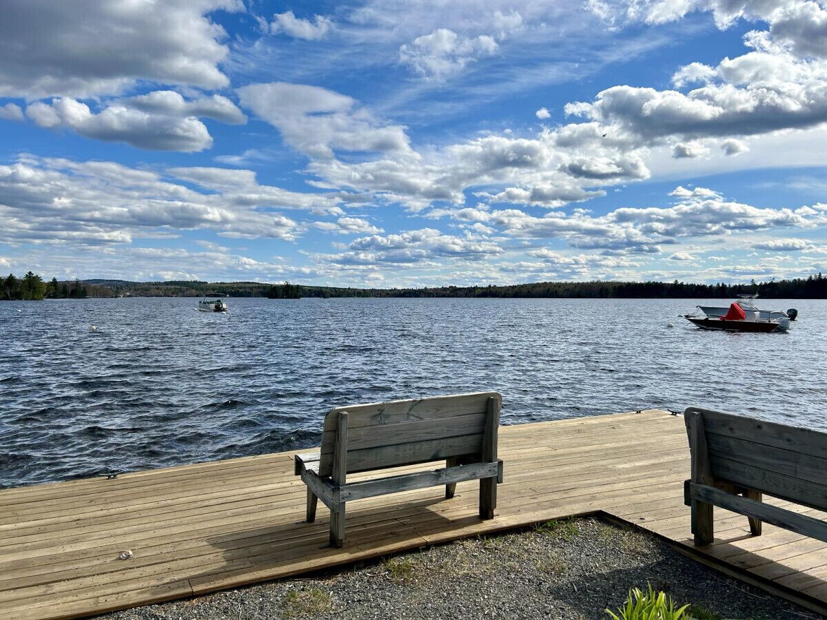 A wooden dock with two benches overlooking a lake.