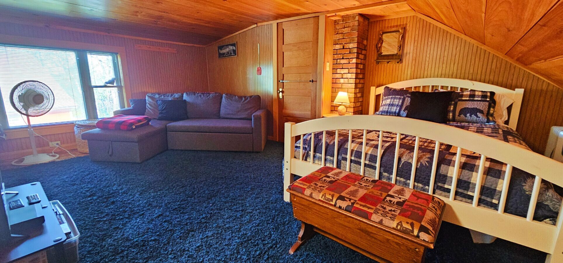 A cozy room with a bed, a sofa, a small table, and a window.