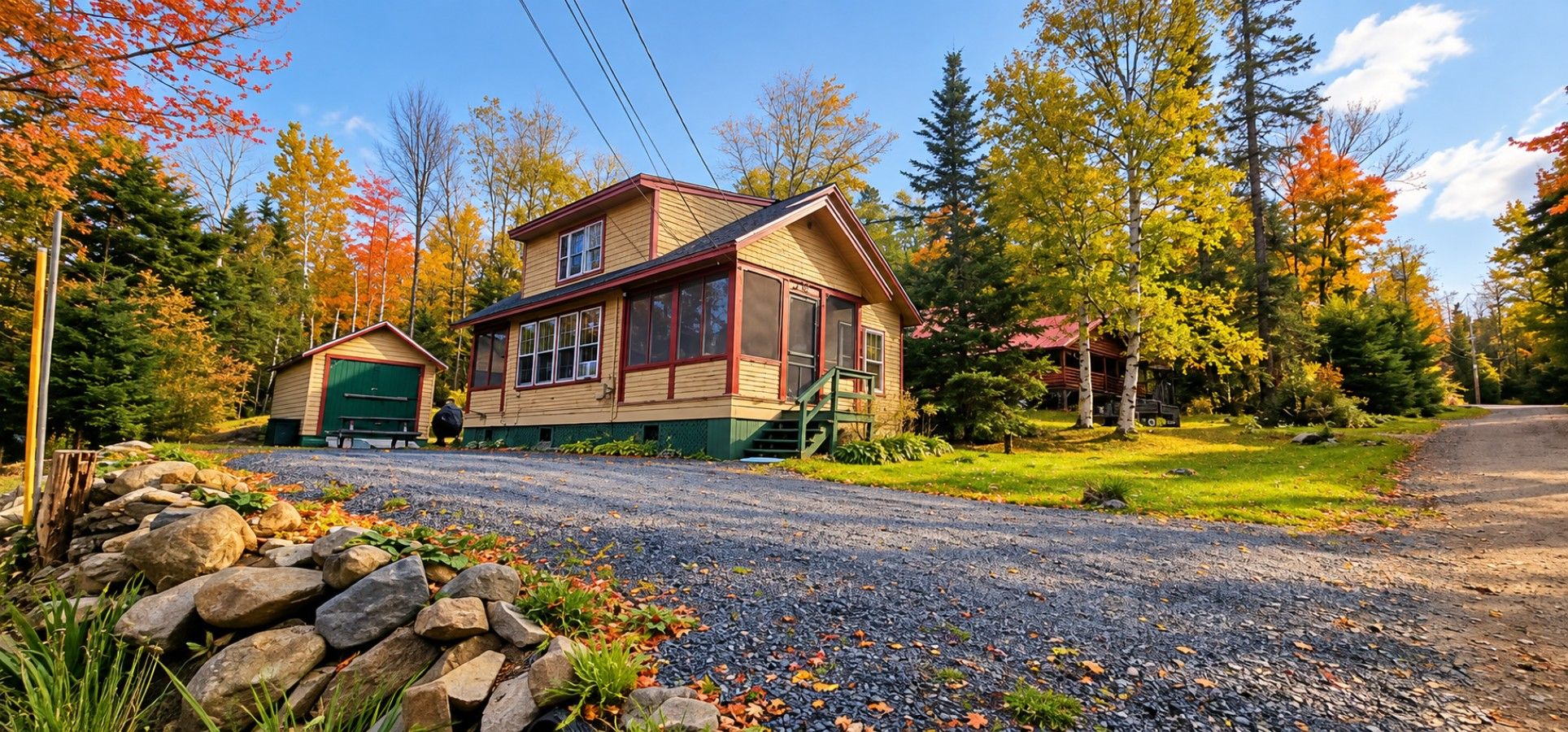 A two-story house with a front porch, a garage, and a driveway leading to a gravel path.
