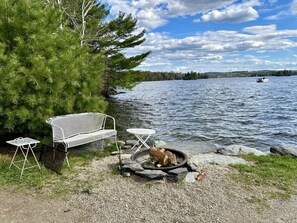 A lakeside setting with a metal bench, a small table, and a fire pit. - BLUE BEAR CABIN- Direct ATV Access*Community Dock*Lake Access*Pet Friendly*A/C*Smart TV (Greenville)